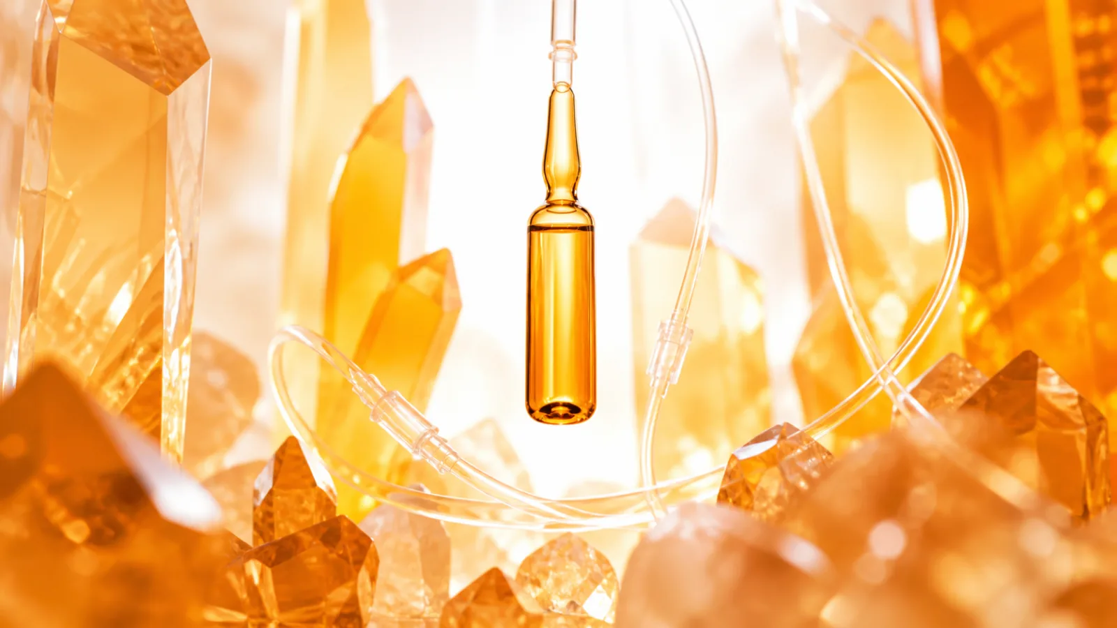 Citrine infusion ampoule suspended among faceted amber glass forms and clear coiled tubing